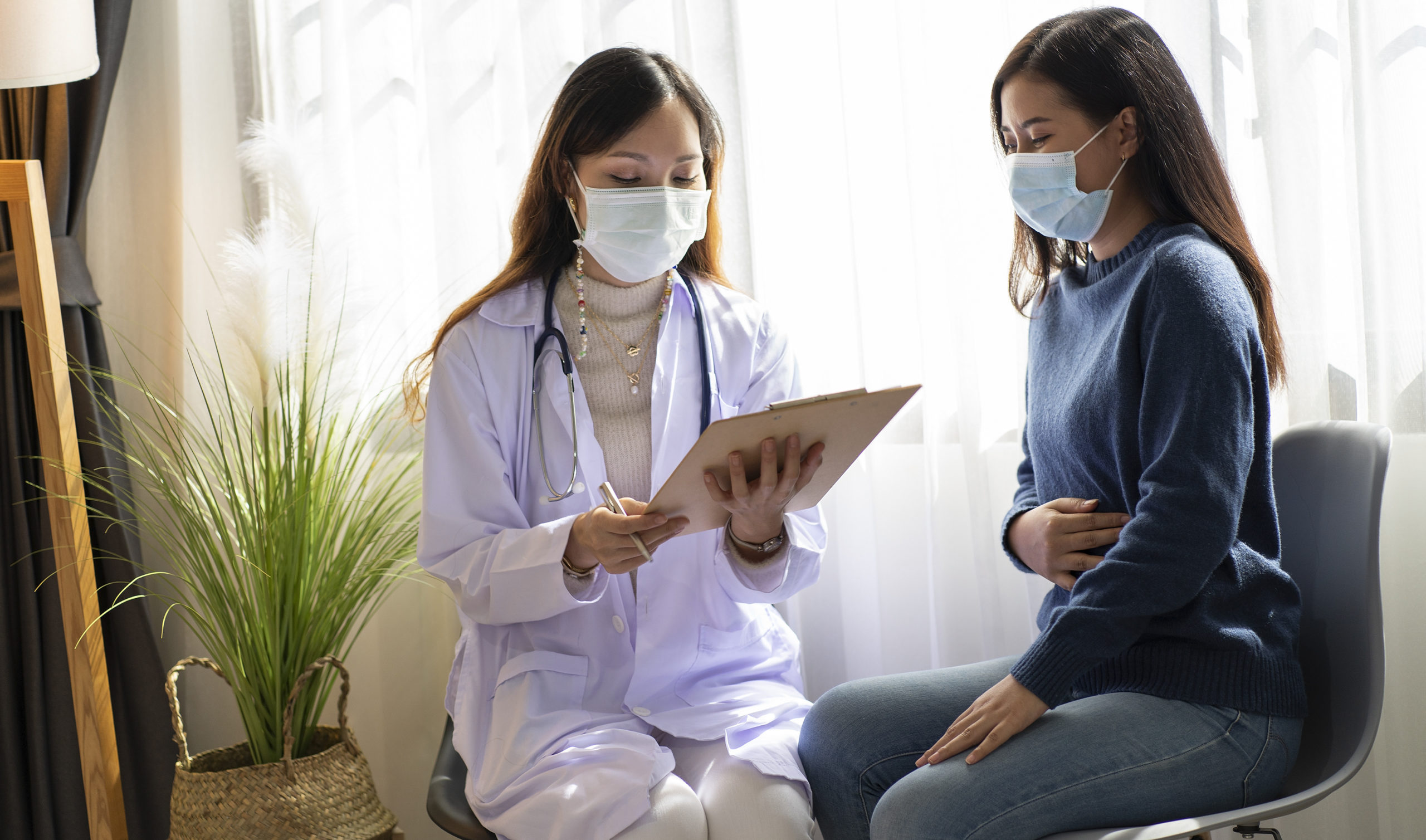 Asian female doctor wearing a mask to treat a female patient wit